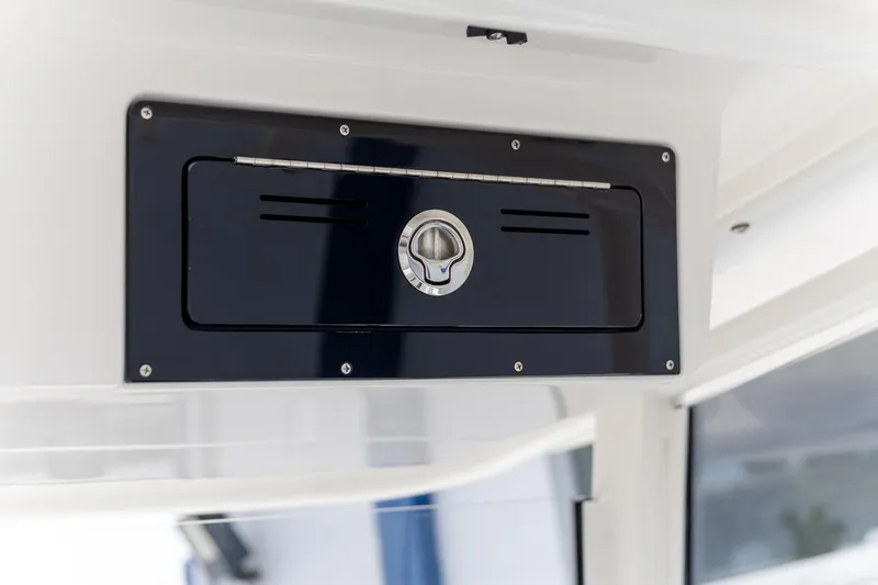 Slide: The Image of 2025 Crevalle 24 HCO boat compartment with sleek black panel and secure latch. - 31