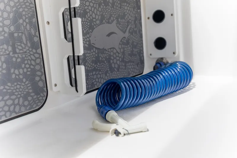 Slide: The Image of Coiled blue hose on 2025 Crevalle 24 HCO boat with fish-patterned panel. - 34
