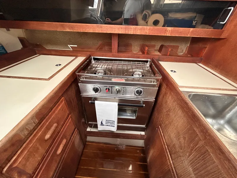 Slide: The Image of 1985 O'Day 35 yacht kitchen with stove, wooden cabinets, and sink. - 12