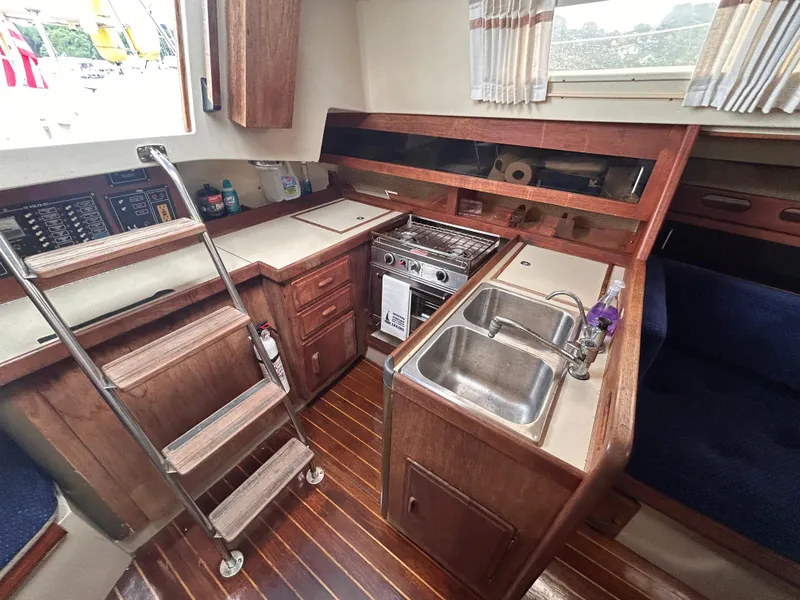 Slide: The Image of Interior of 1985 O'Day 35 sailboat with kitchen, sink, stove, and wooden cabinetry. - 13