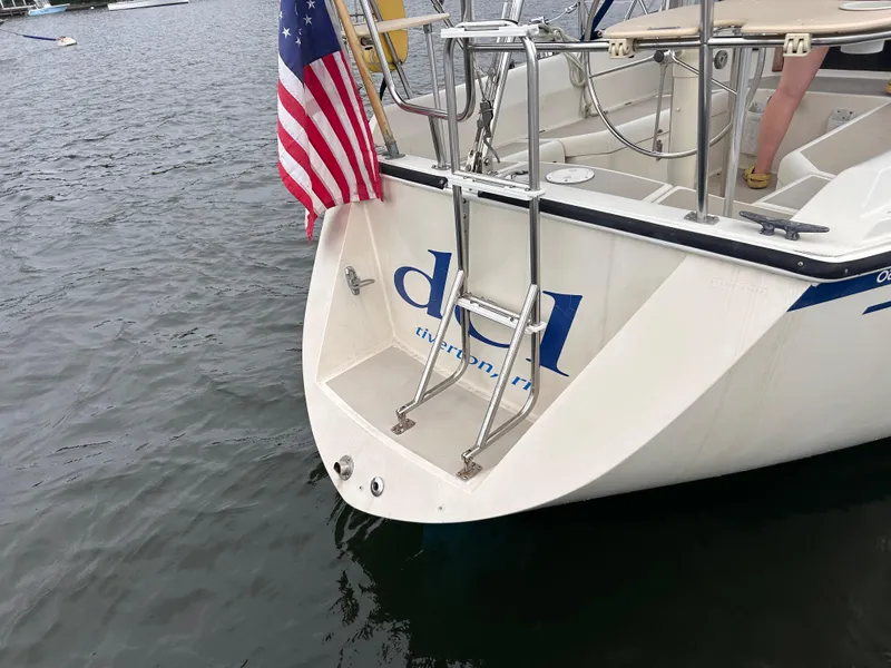 Slide: The Image of 1985 O'Day 35 sailboat stern with ladder and American flag on water. - 2
