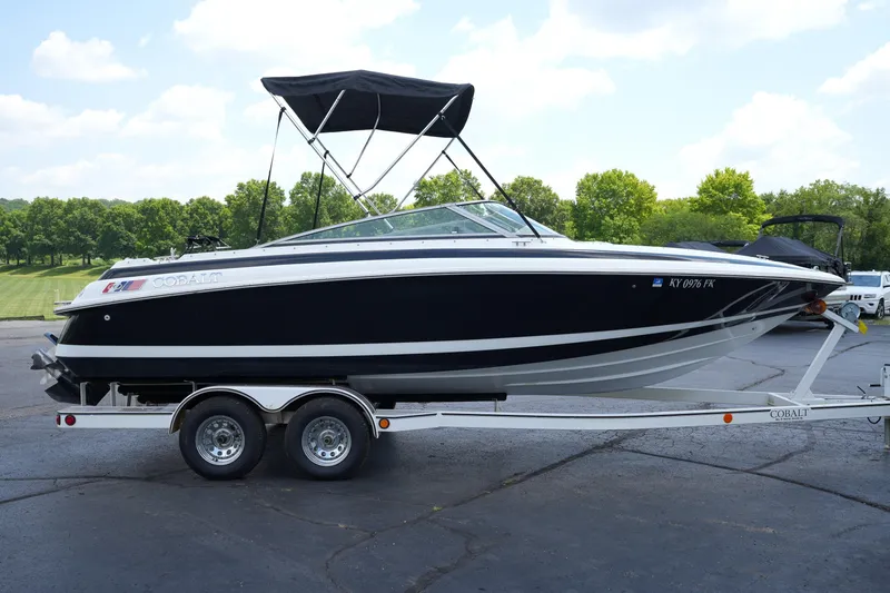 Slide: The Image of 1997 Cobalt 232 boat on trailer, black and white design, parked outdoors. - 3