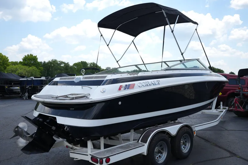 Slide: The Image of 1997 Cobalt 232 boat on trailer with canopy, parked outdoors under a blue sky. - 4