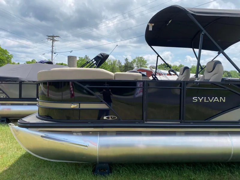 Slide: The Image of 2025 Sylvan L1 LZ Tritoon with Mercury 150HP engine, parked on grass under cloudy sky. - 16