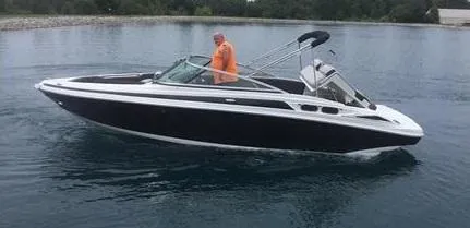The Image of 2025 Crownline 220 SS boat cruising on a calm lake with a person onboard. - 1