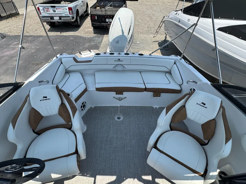 Slide: The Image of 2025 Stingray 201 DC boat interior with white and brown seating, steering wheel, and spacious layout. - 17