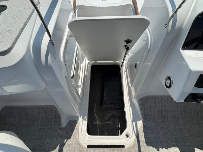 Slide: The Image of 2025 Stingray 201 DC boat interior storage compartment, open lid, gray flooring. - 18