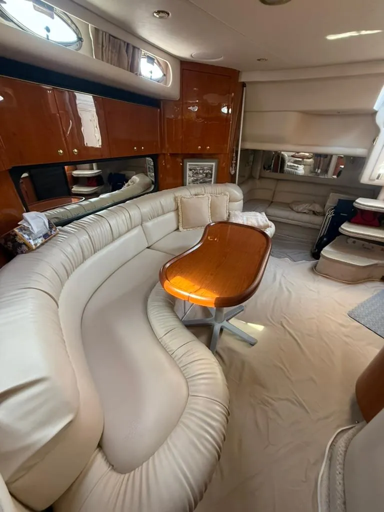 Slide: The Image of Interior of 2000 Sea Ray 380 Sundancer with curved seating and wooden table. - 10
