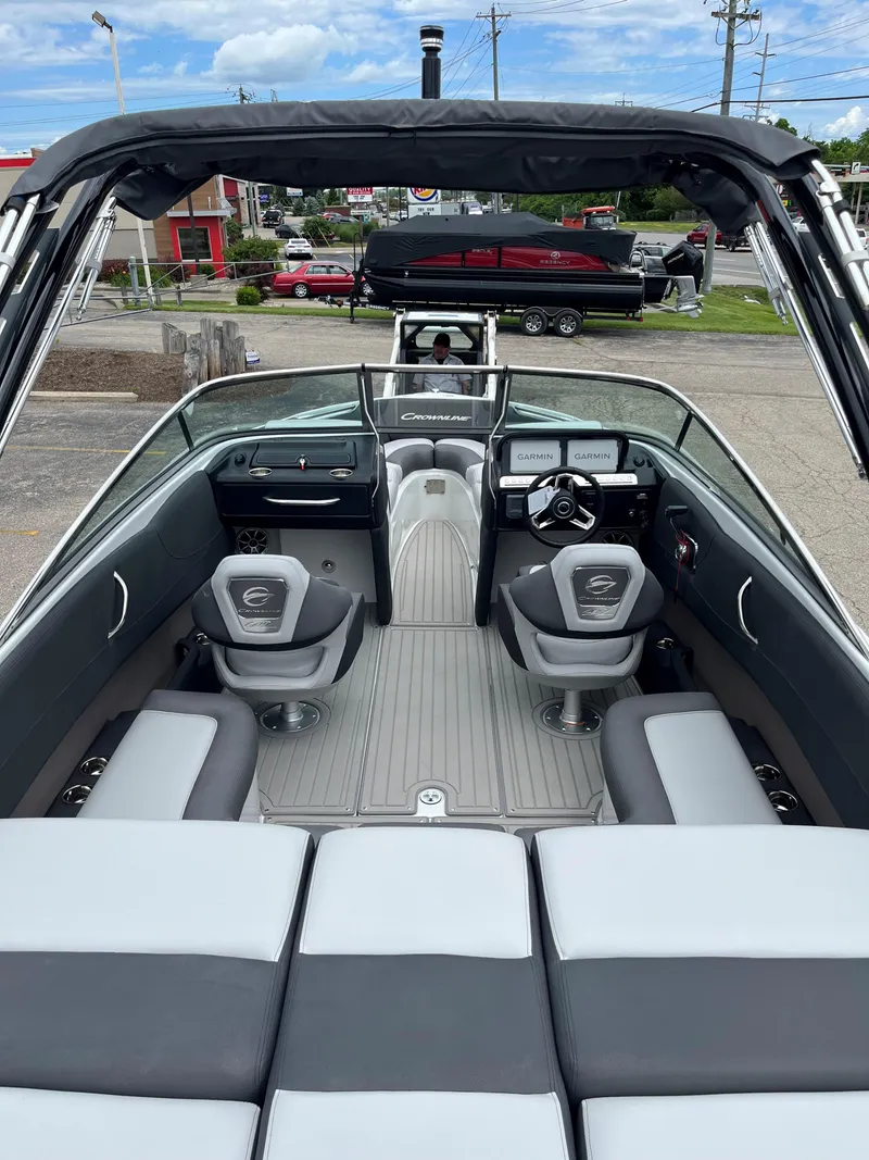 Slide: The Image of 2025 Crownline 240 SS boat interior with modern seating and dashboard, parked outdoors. - 10
