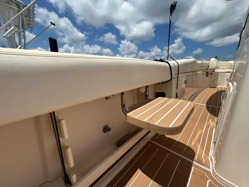 Slide: The Image of 2019 Grady-White Canyon 306 boat interior with wooden deck and seating under a blue sky. - 10
