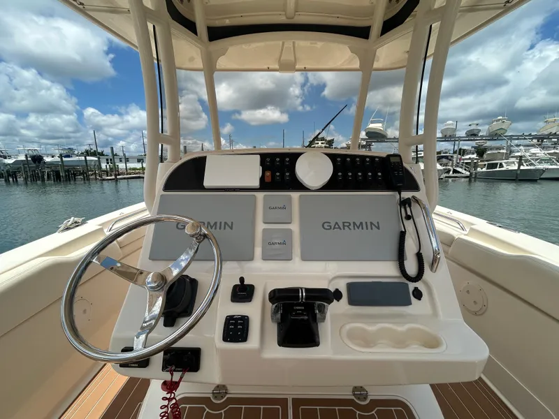 Slide: The Image of 2019 Grady-White Canyon 306 helm with Garmin navigation, docked at marina under blue sky. - 11