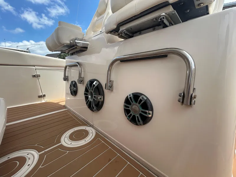 Slide: The Image of 2019 Grady-White Canyon 306 boat interior with speakers and seating, under a clear blue sky. - 14