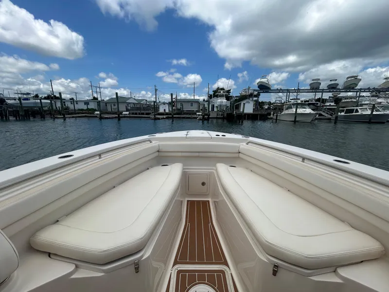 Slide: The Image of 2019 Grady-White Canyon 306 boat interior with cushioned seating, docked at marina under cloudy sky. - 20