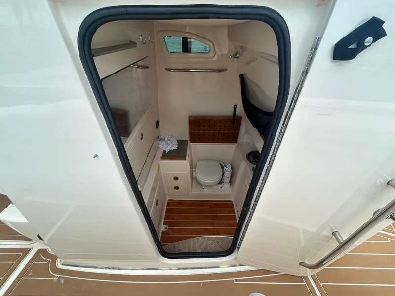 Slide: The Image of 2019 Grady-White Canyon 306 boat interior with compact bathroom and wooden flooring. - 28