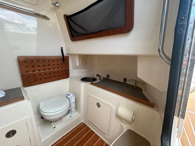 Slide: The Image of 2019 Grady-White Canyon 306 boat interior with toilet and sink, featuring wood accents. - 31