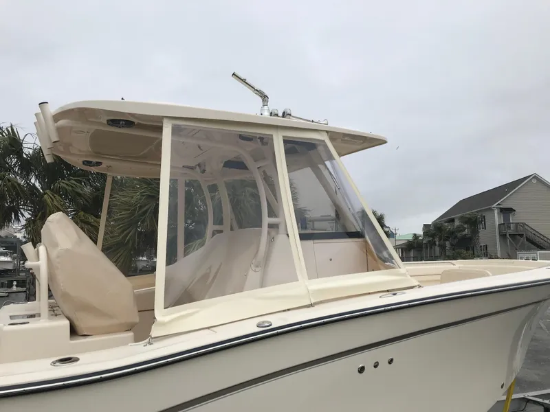 Slide: The Image of 2019 Grady-White Canyon 306 boat with enclosed helm, docked near palm trees. - 33