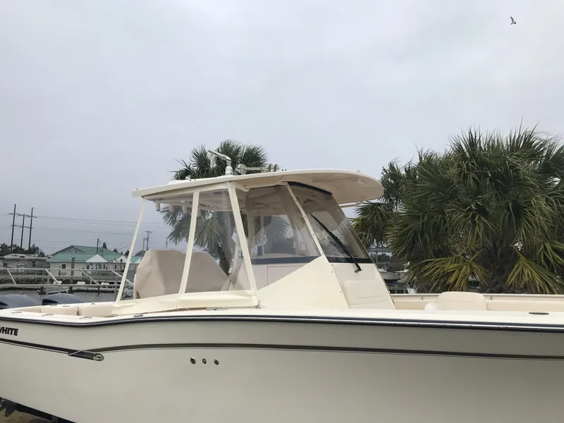 Slide: The Image of 2019 Grady-White Canyon 306 boat docked near palm trees under cloudy sky. - 34