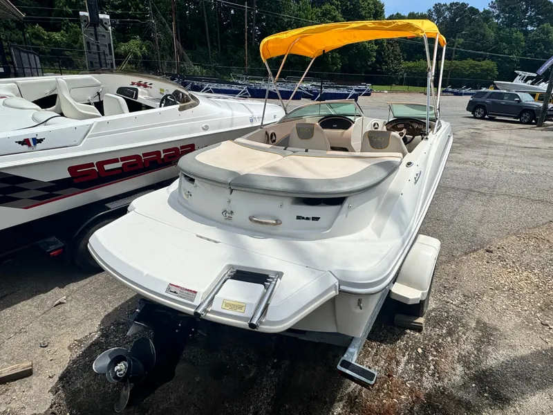 Slide: The Image of 2008 Sea Ray 185 Sport boat with yellow canopy, parked beside another boat. - 6