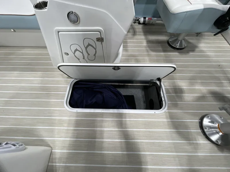 Slide: The Image of 2025 South Bay S224 Chill boat interior with open storage compartment on striped flooring. - 19