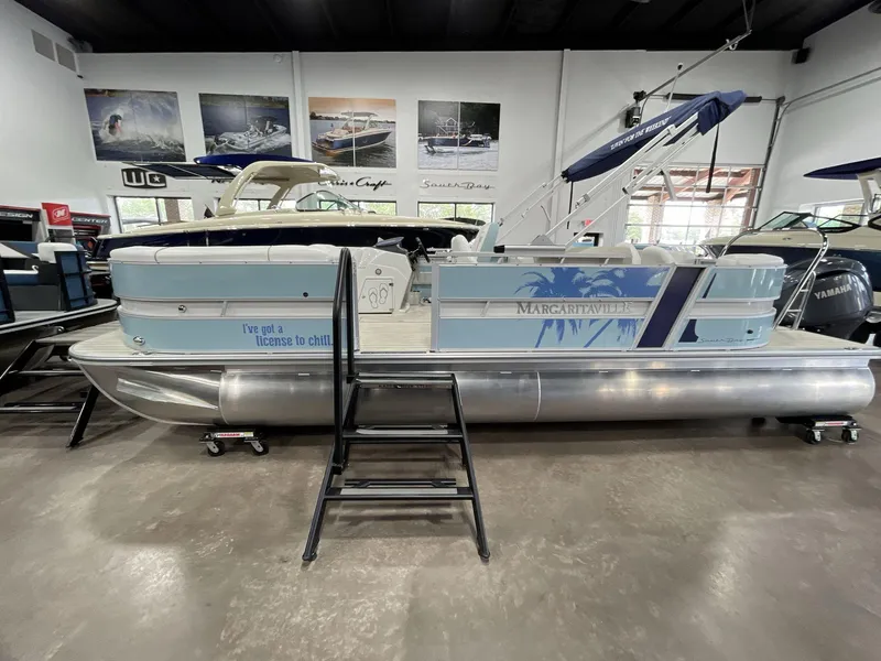 Slide: The Image of 2025 South Bay S224 Chill pontoon boat in showroom, featuring "Margaritaville" theme and "license to chill" slogan. - 2