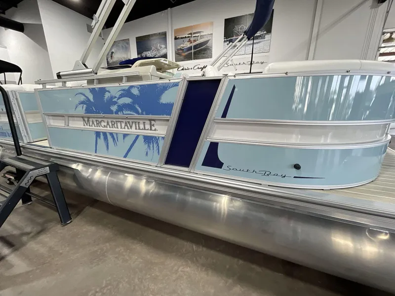 Slide: The Image of 2025 South Bay S224 Chill pontoon boat with Margaritaville theme, displayed indoors. - 7
