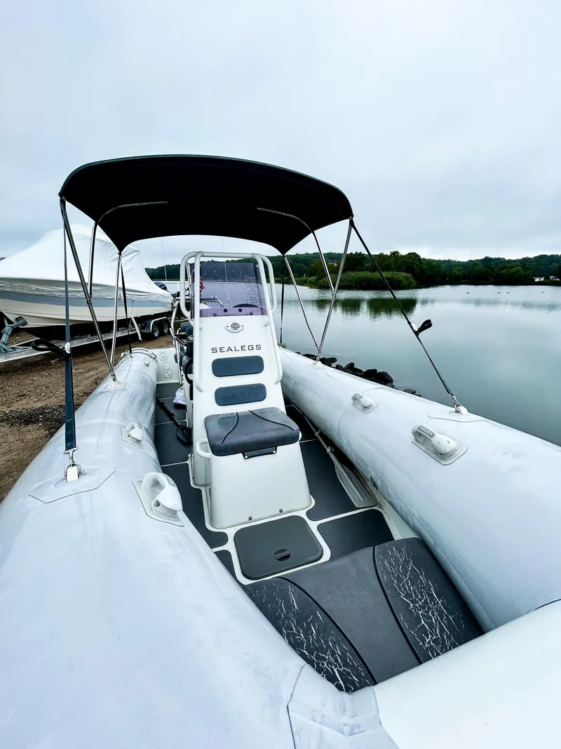 Slide: The Image of 2014 Sealegs 7.1m RIB with canopy, docked by a serene lake. - 5