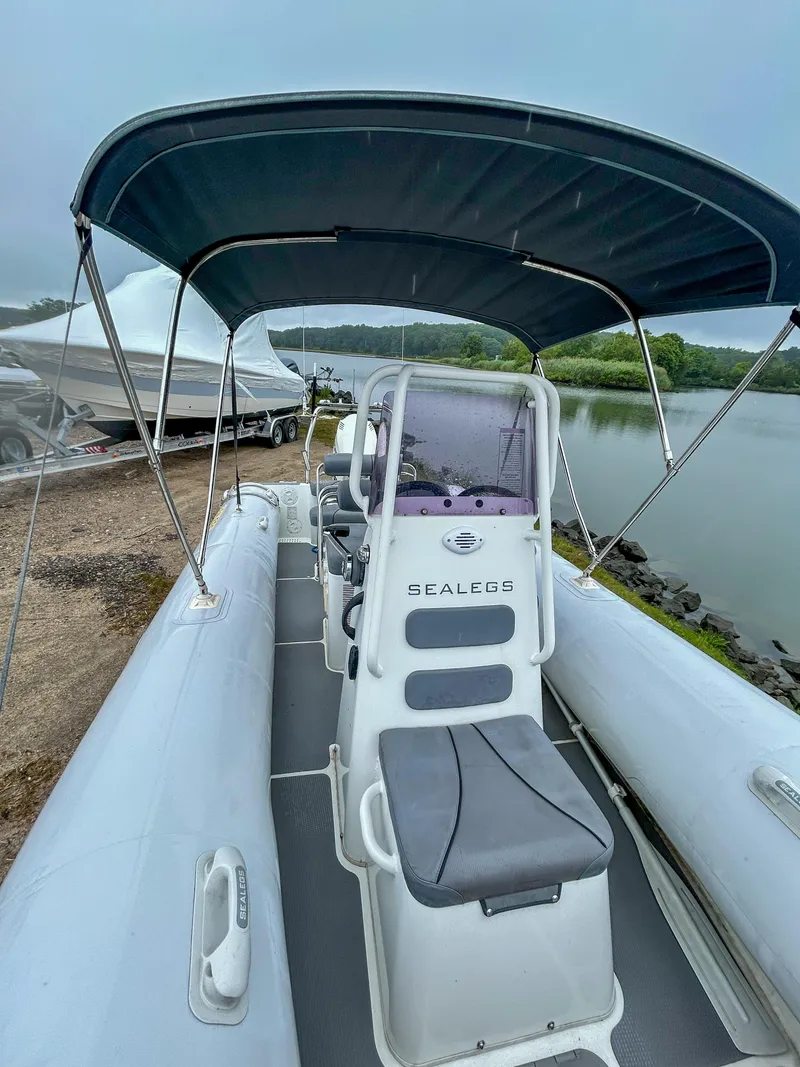 Slide: The Image of 2014 Sealegs 7.1m RIB boat with canopy, docked by a serene lake. - 8