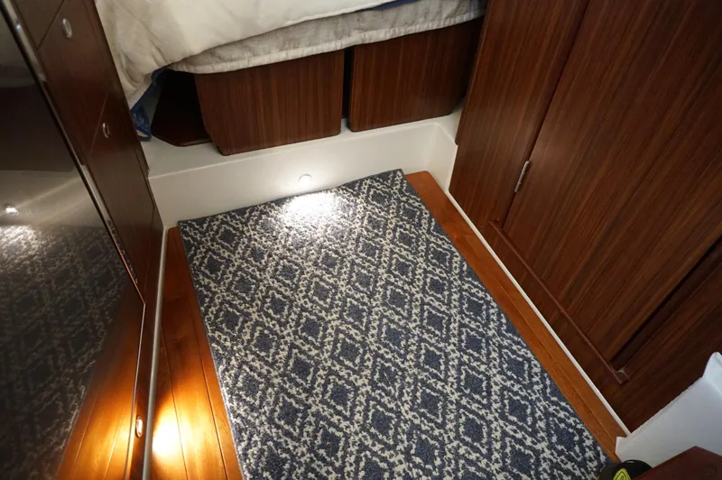 Slide: The Image of 2023 Pursuit OS 355 Offshore cabin interior with patterned rug and wooden cabinetry. - 38