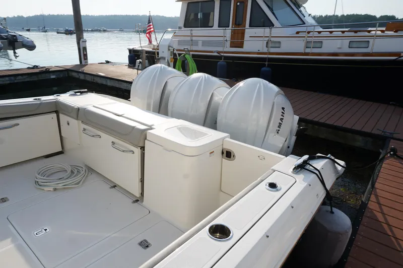 Slide: The Image of 2023 Pursuit OS 355 Offshore boat docked, featuring triple Yamaha outboard engines. - 6