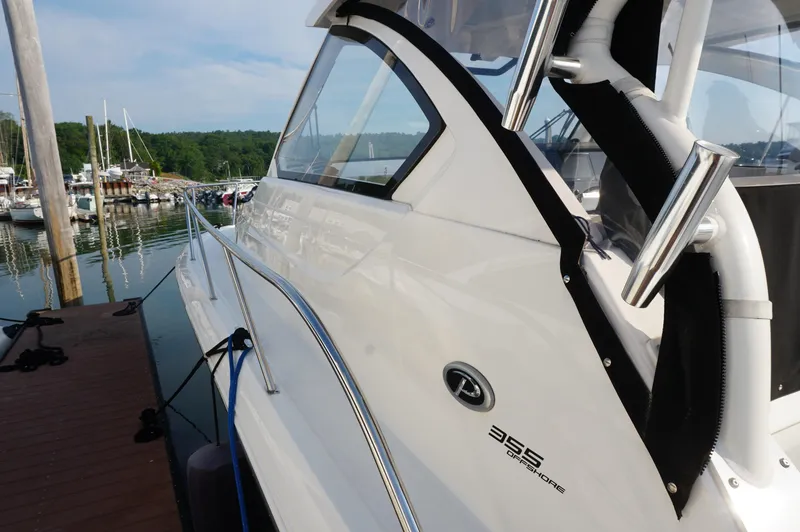 Slide: The Image of 2023 Pursuit OS 355 Offshore boat docked at marina, showcasing sleek design and chrome details. - 7