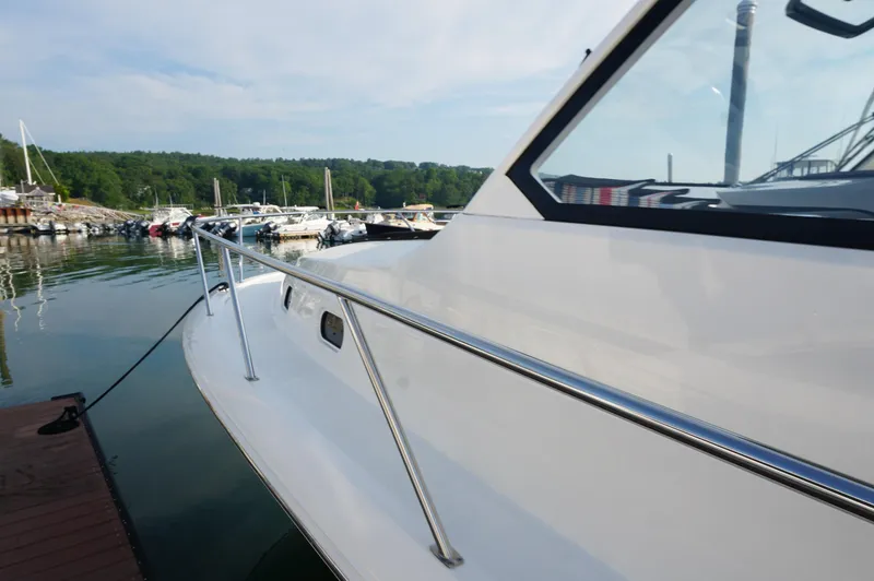 Slide: The Image of 2023 Pursuit OS 355 Offshore boat docked at a marina, surrounded by calm water. - 8