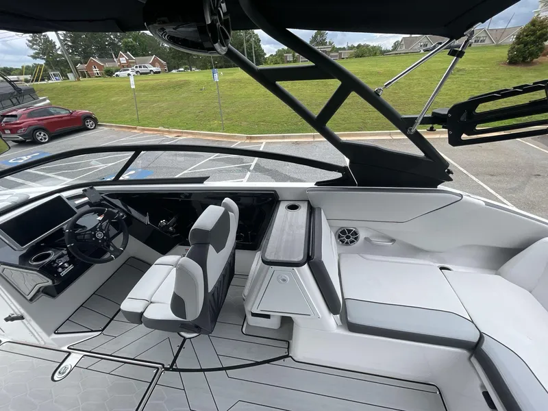 Slide: The Image of 2024 Yamaha Boats 252XE interior with sleek seating and modern dashboard in a parking lot. - 16