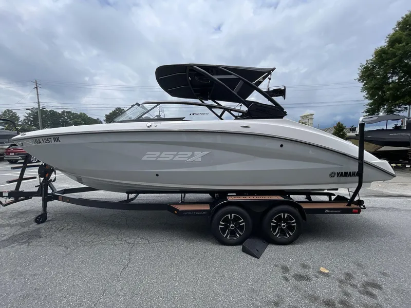 Slide: The Image of 2024 Yamaha Boats 252XE on trailer, side view, cloudy sky background. - 2