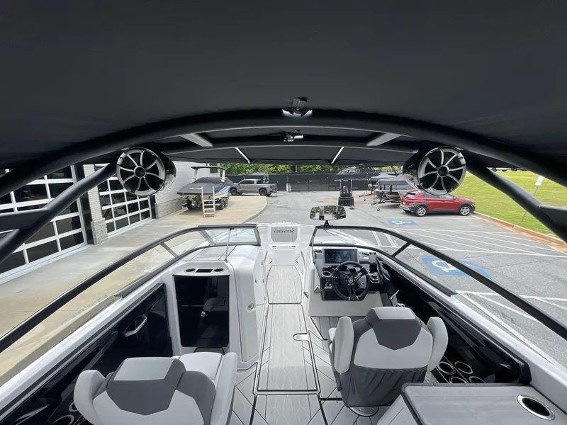 Slide: The Image of 2024 Yamaha Boats 252XE interior with modern helm, seating, and speakers, parked outdoors. - 22