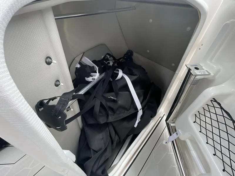 Slide: The Image of Storage compartment in 2024 Yamaha Boats 252XE, featuring black bag and accessories. - 25