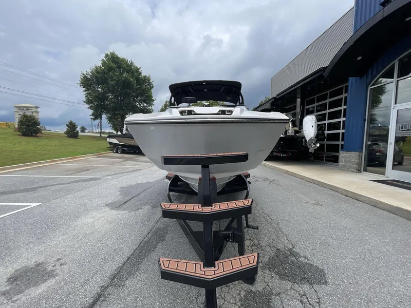 Slide: The Image of 2024 Yamaha Boats 252XE on trailer, parked outside dealership under cloudy sky. - 7