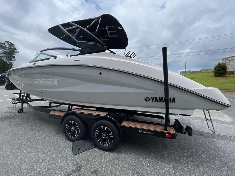 Slide: The Image of 2024 Yamaha Boats 252XE on trailer, sleek design, parked outdoors under cloudy sky. - 8