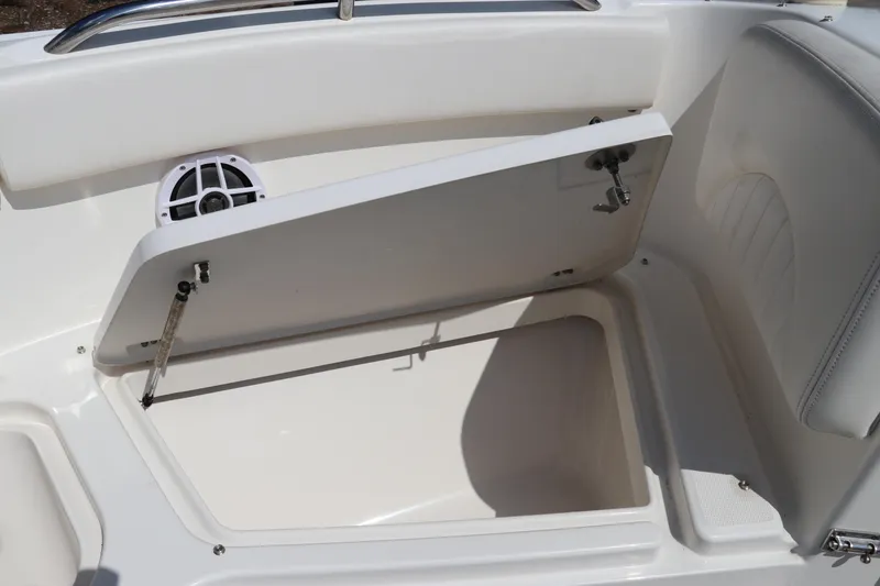 Slide: The Image of 2008 Robalo R227 Dual Console boat storage compartment with open lid and speaker. - 48