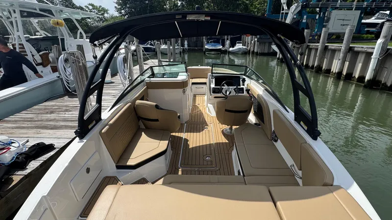 Slide: The Image of 2022 Sea Ray SPX 230 boat with tan seating and black canopy docked at marina. - 5