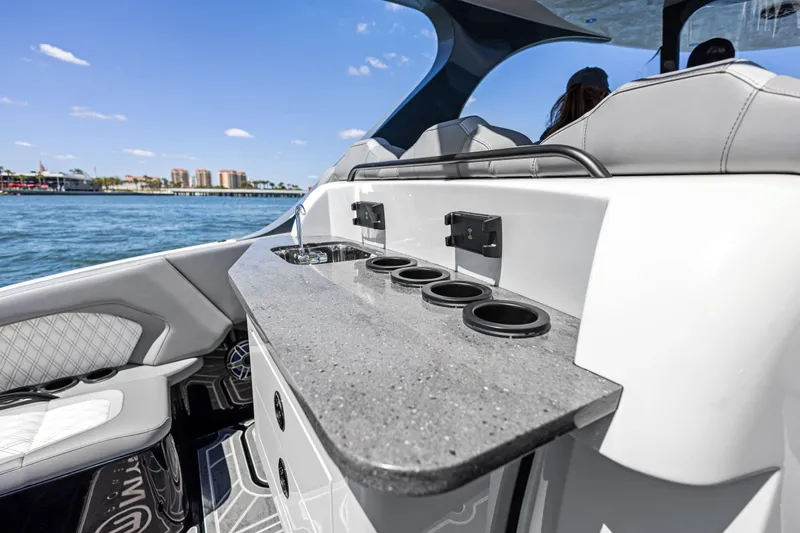 Slide: The Image of 2026 Mystic Powerboats M4200 interior with sleek countertop and cup holders on a sunny day. - 27