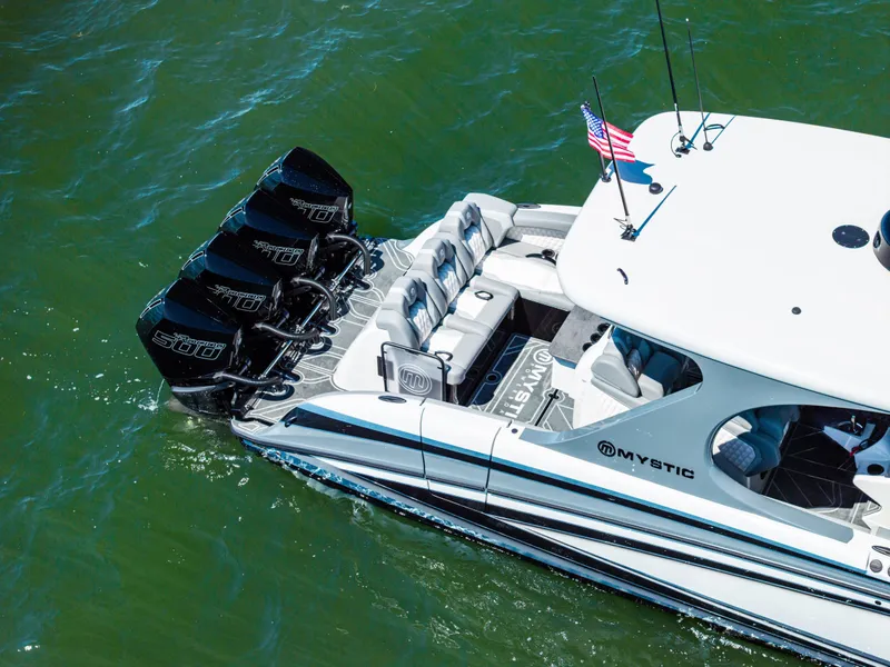 Slide: The Image of 2026 Mystic Powerboats M4200 with quad engines cruising on water. - 46