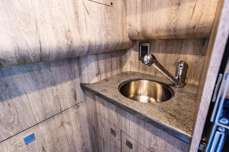 Slide: The Image of Compact sink area in 2026 Mystic Powerboats M4200, featuring wood finish and modern faucet. - 6