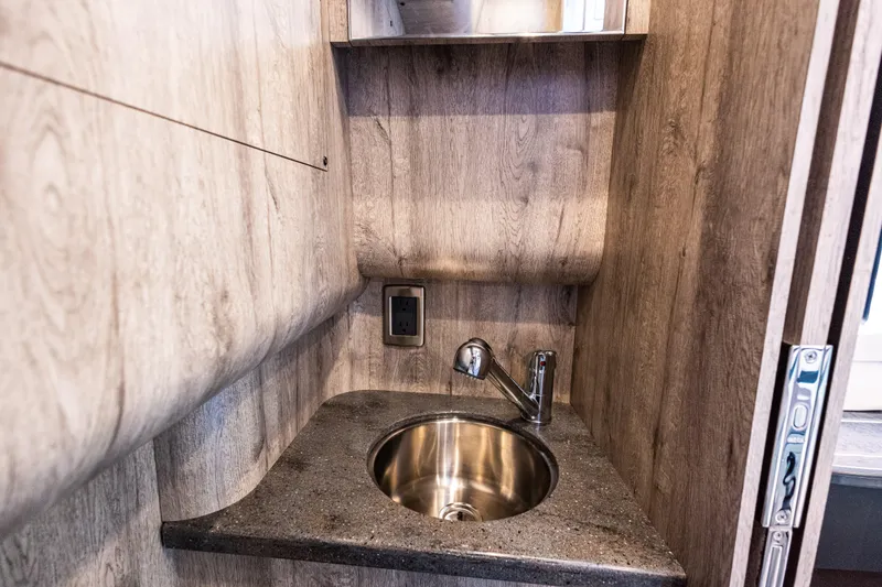 Slide: The Image of 2026 Mystic Powerboats M4200 interior sink with wood paneling and modern faucet. - 7