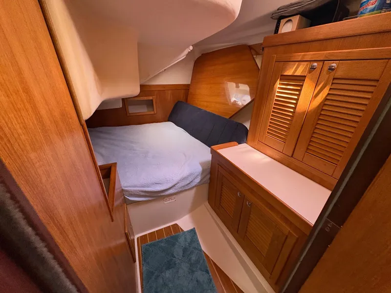 Slide: The Image of Cozy cabin interior of a 2006 Catalina 350 sailboat with wooden cabinetry and a comfortable bed. - 27