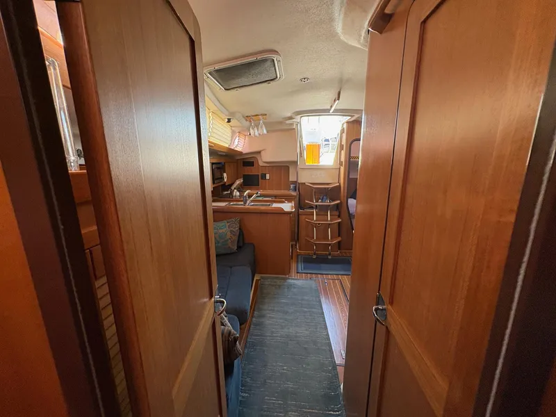Slide: The Image of Interior of a 2006 Catalina 350 sailboat, featuring wooden cabinetry and cozy seating. - 42