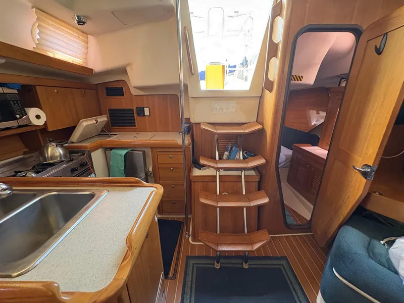 Slide: The Image of Interior of a 2006 Catalina 350 sailboat, featuring a compact kitchen and wooden cabinetry. - 43