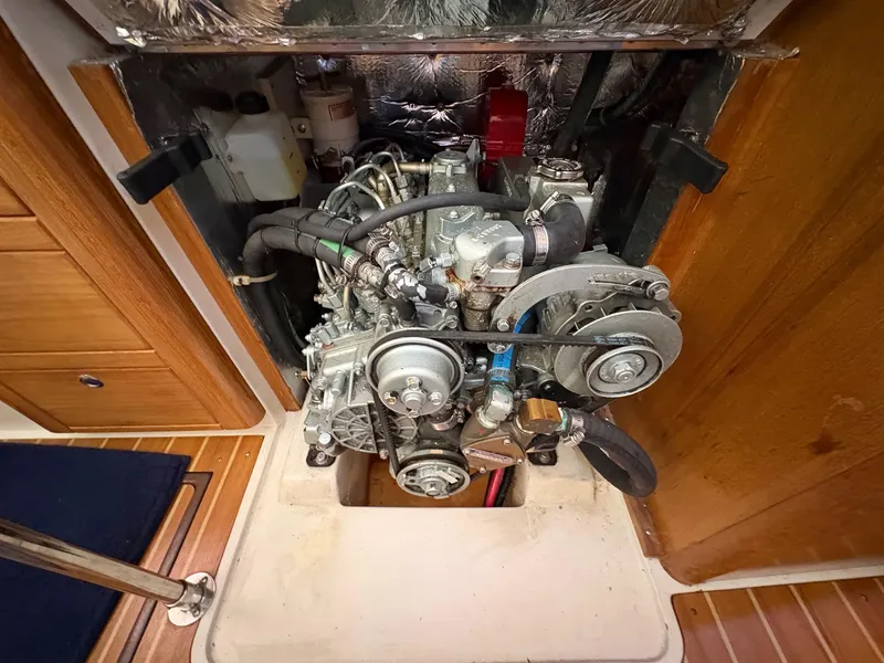 Slide: The Image of Engine compartment of a 2006 Catalina 350 sailboat, showcasing mechanical components and wooden interior. - 48