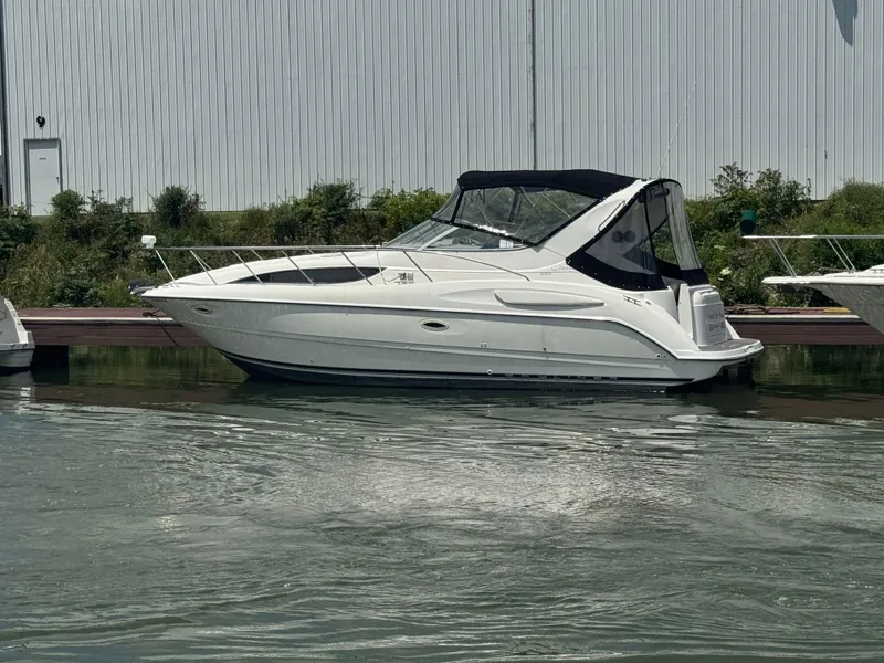 The Image of 1999 Bayliner 3055 Ciera boat docked on calm water near a metal building. - 0