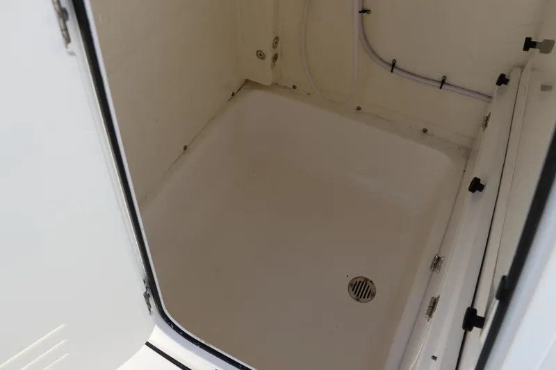 Slide: The Image of 2022 Tidewater 232 SS boat storage compartment with drain and white interior. - 34