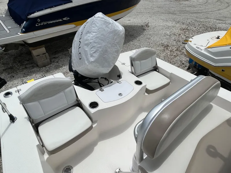 Slide: The Image of 2016 Robalo 206 Cayman boat interior with seating and covered motor, parked on gravel. - 18